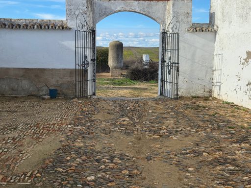 Entrada con puertas de metal en un paisaje despejado y suelo de piedras.